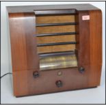 A vintage 20th century Peto Scott wooden cased valve radio. Having a central speaker to the front,