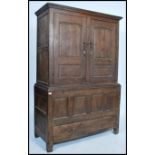 An 18th / 19th century oak armoire wardrobe having twin fielded panel doors over a panelled front