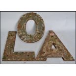 A set of 3 large early 20th century cast iron shop external advertising sign letters being dug up