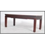 A 20th century Chinese hardwood opium style coffee table being raised on squared legs with a