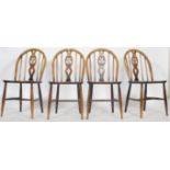 A set of 4 20th century Ercol beech and elm wood ' fleur de lys ' dining chairs being raised on