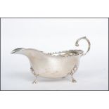 A silver hallmarked sauce boat raised on cabriolet legs with a curved handle and scalloped edge.