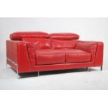 A contemporary red leather Italian sofa raised on