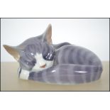 A Royal Copenhagen ceramic sleeping cat figurine 057 along with a Royal Doulton Images Of Nature cat