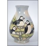A Moorcroft Pottery Puffin pattern baluster vase decorated with puffins against a mountainous