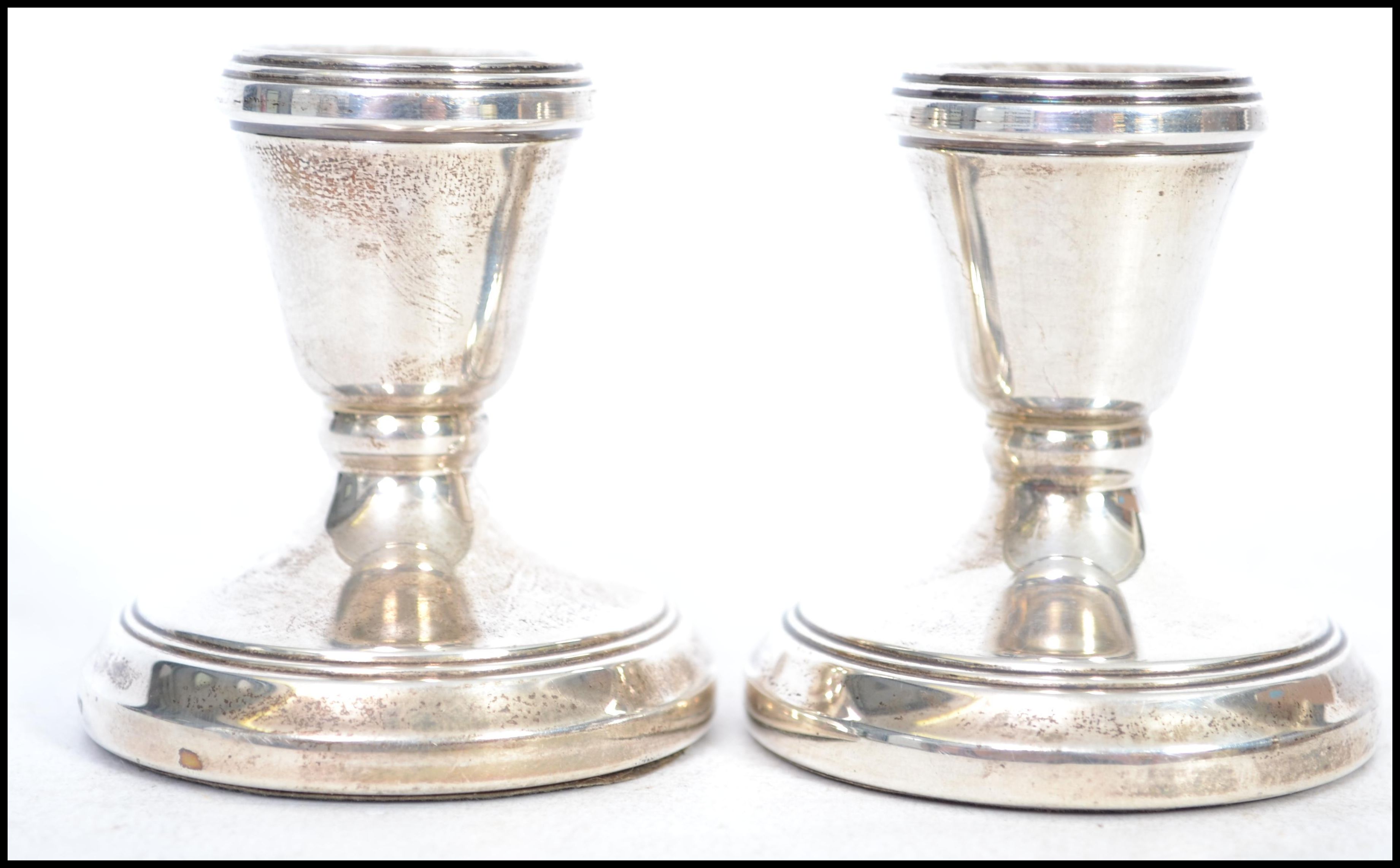 A pair of hallmarked silver candlesticks of squat