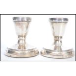 A pair of hallmarked silver candlesticks of squat