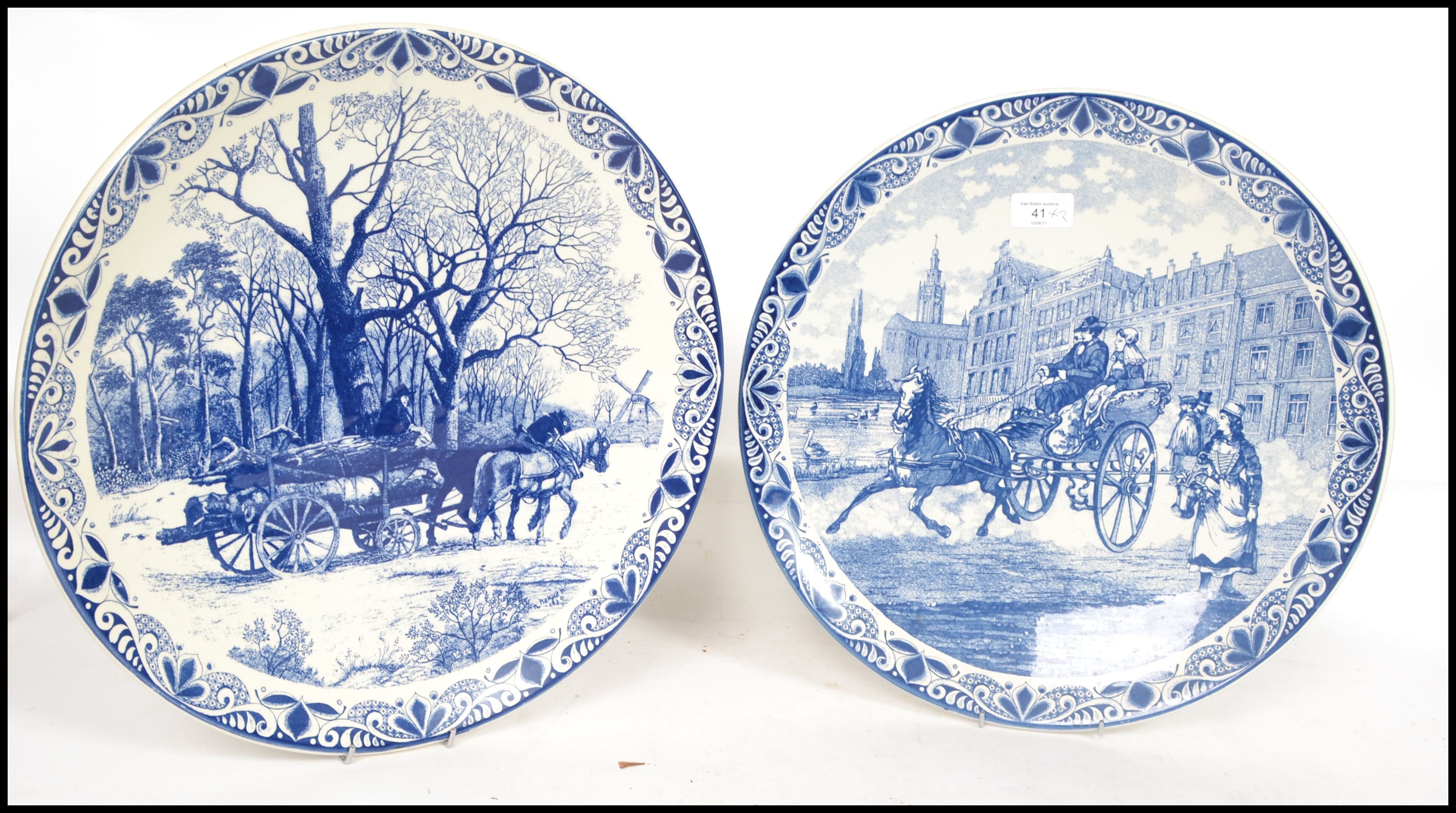 Two 20th century Delft ceramic wall hanging charger plates each having a central tondo depicting