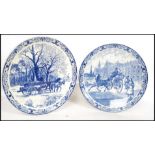 Two 20th century Delft ceramic wall hanging charger plates each having a central tondo depicting