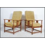 A pair of 1920's oak barleytwist fireside armchairs being raised on barleytwist legs united by