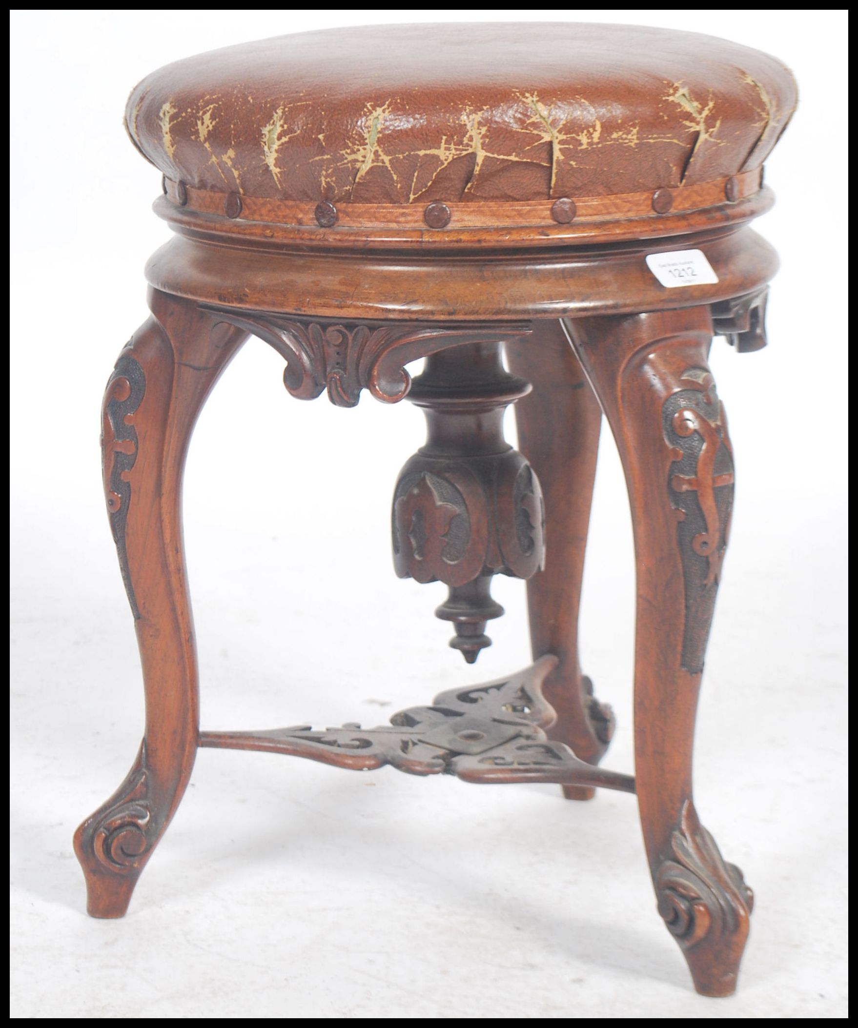 A Victorian tripod piano stool in walnut having lavishly carved cabriole legs and a faux leather