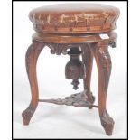 A Victorian tripod piano stool in walnut having lavishly carved cabriole legs and a faux leather