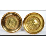 A pair of 20th century large wall hanging brass chargers depicting people - merchants to the centre,