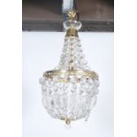 A large early 20th century Empire style brass drop chandelier having multiple faceted crystal