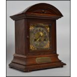 An oak mantel clock having dome top with a bevelled bezel and a silvered and gilt face, the clock is