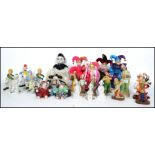 A collection of ceramic clown figurines along with a group of clown, jester and harlequin dolls.