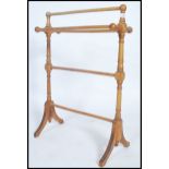 A Victorian style beech wood towel rail with out swept legs, turned rails and finials tops