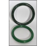 Two 20th century Chinese jade bangles of differing shades of green one being a very deep rich