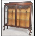 A 1930's mahogany Queen Anne revival china display cabinet being raised on ball and claw feet with