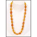 A vintage early 20th century single row, graduated, olive-shaped amber bead necklace, strung on