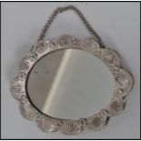 An Indian silver white metal small ladies vanity mirror on chain having a floral and leaf spray to