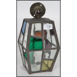 An early 20th century Arts & Crafts hexagonal glass and brass porch lantern, the stained glass