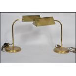 A pair of vintage style 20th century brass bankers lamps raised on circular bases with arched