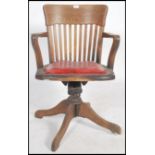 A 1930's Industrial oak office swivel chair being raised on a quadruped base with swivel column. The