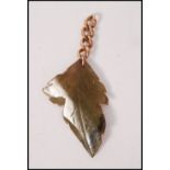 A 9ct gold and jade leaf pendant. The carved green jade in the form of a leaf being set to a 9ct