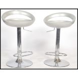 A pair of 20th century chrome and silvered bar stools being raised on chrome terraced bases, gas