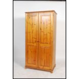 A contemporary antique style pine double wardrobe having plinth base with bun feet, two full