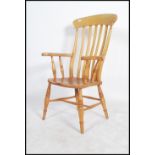 A Victorian style beech and elm wood windsor armchair having turned legs, saddle seat with shaped