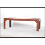A Chinese style walnut rectangular coffee table with plain flush panelled top and raised on square