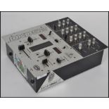 A vintage DX052 DJ mixer board in black and silver with dials to front.