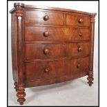 A Victorian large bow front flame mahogany chest of drawers raised on turned legs with columns to