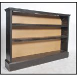 A Victorian ebonised open window bookcase cabinet being raised on a plinth base with fixed