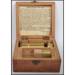 A vintage early 20th century brass miniature microscope complete in a fitted wooden case with a