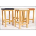 A set of four vinyl topped multi coloured stools in a square form and straight square legs united by