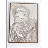 A sterling silver Russian religious Icon mounted on a wooden back plate depicting The Virgin Mary