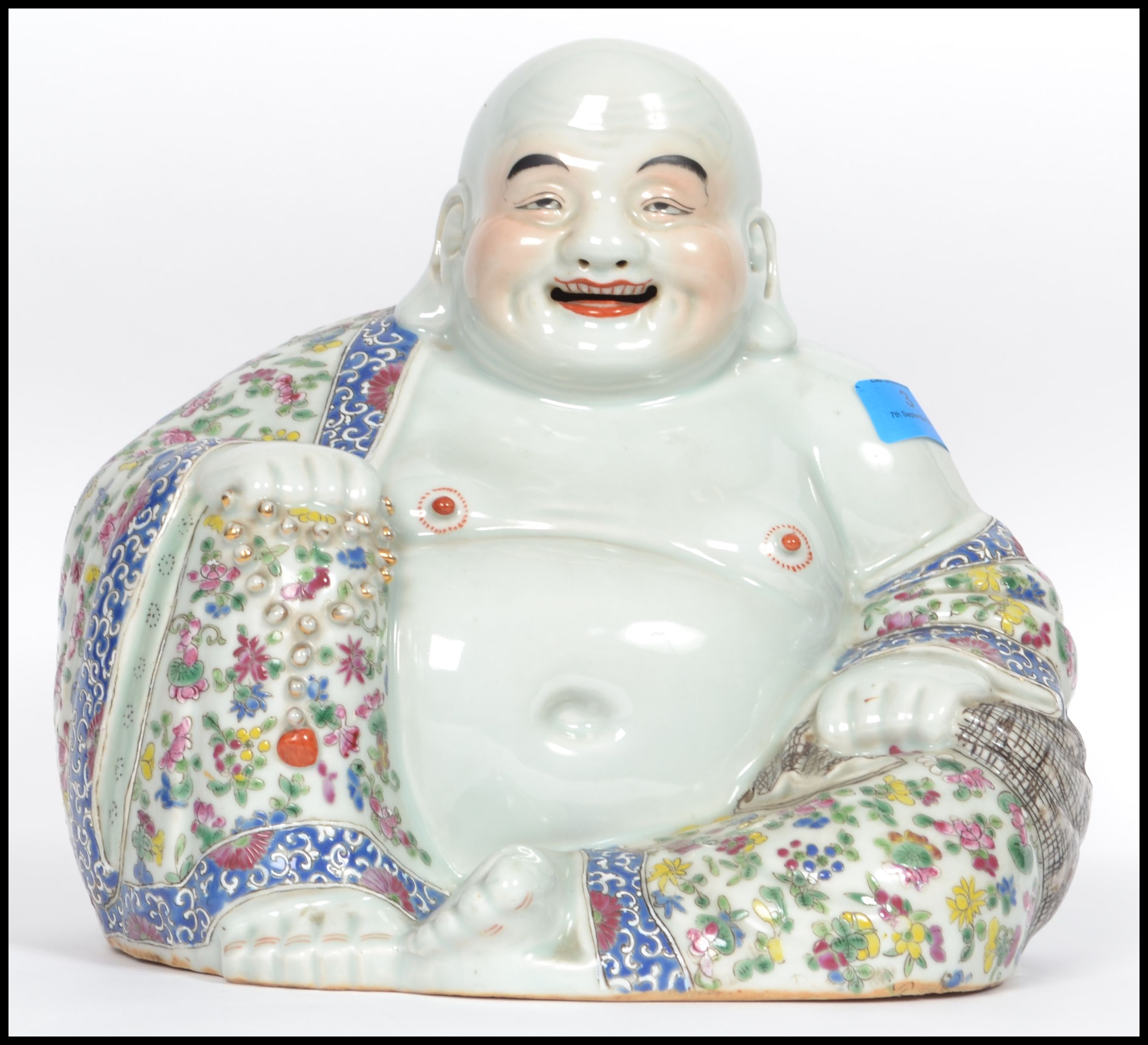 An Oriental ceramic large seated laughing Buddha decorated in famille rose patterned robes holding