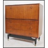 A 1970's teak G-plan librenza bureau chest of drawers being raised on an ebonized suspension set