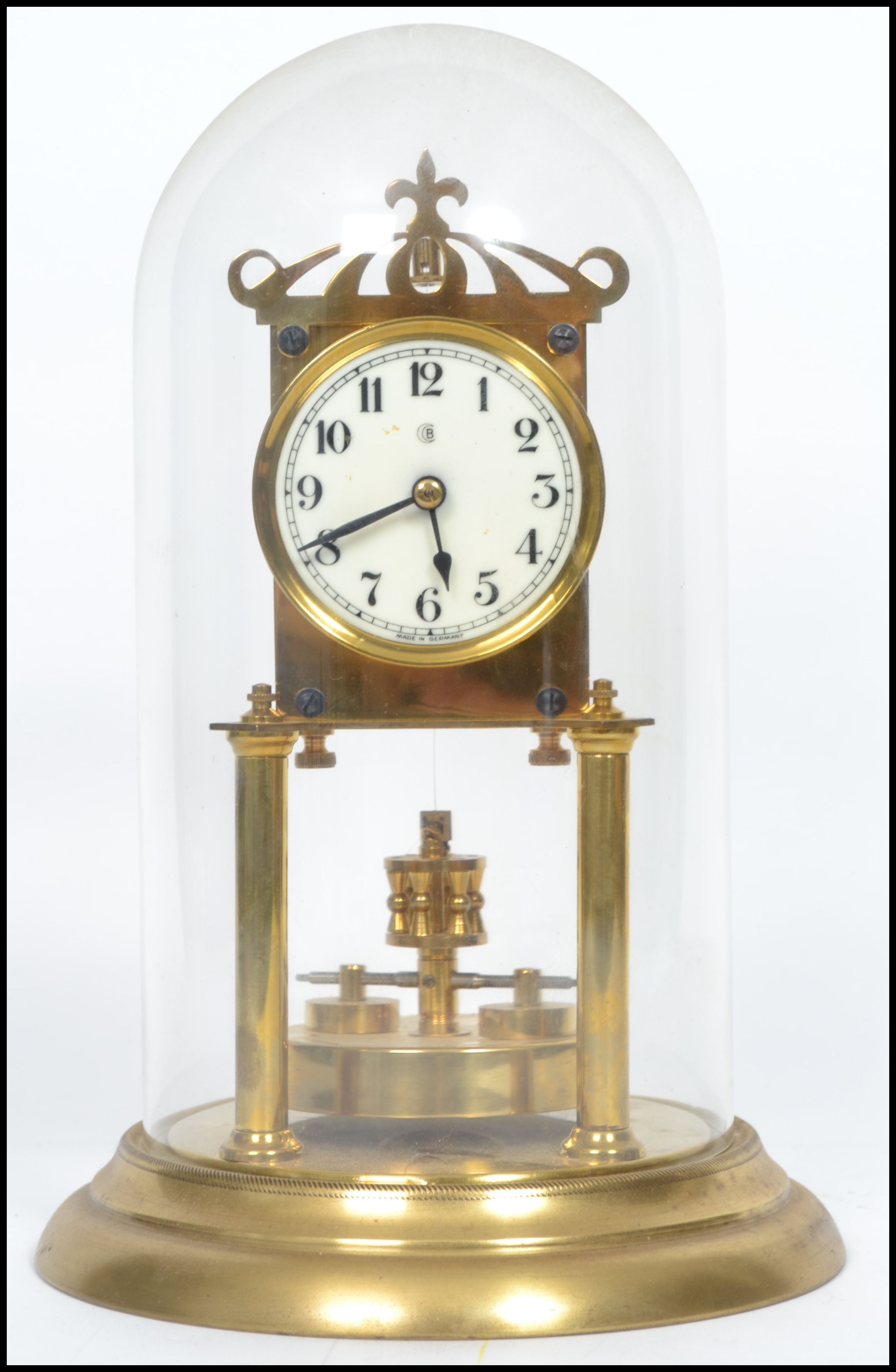 A 20th century glass domed brass anniversary clock raised on a stepped circular base with twin