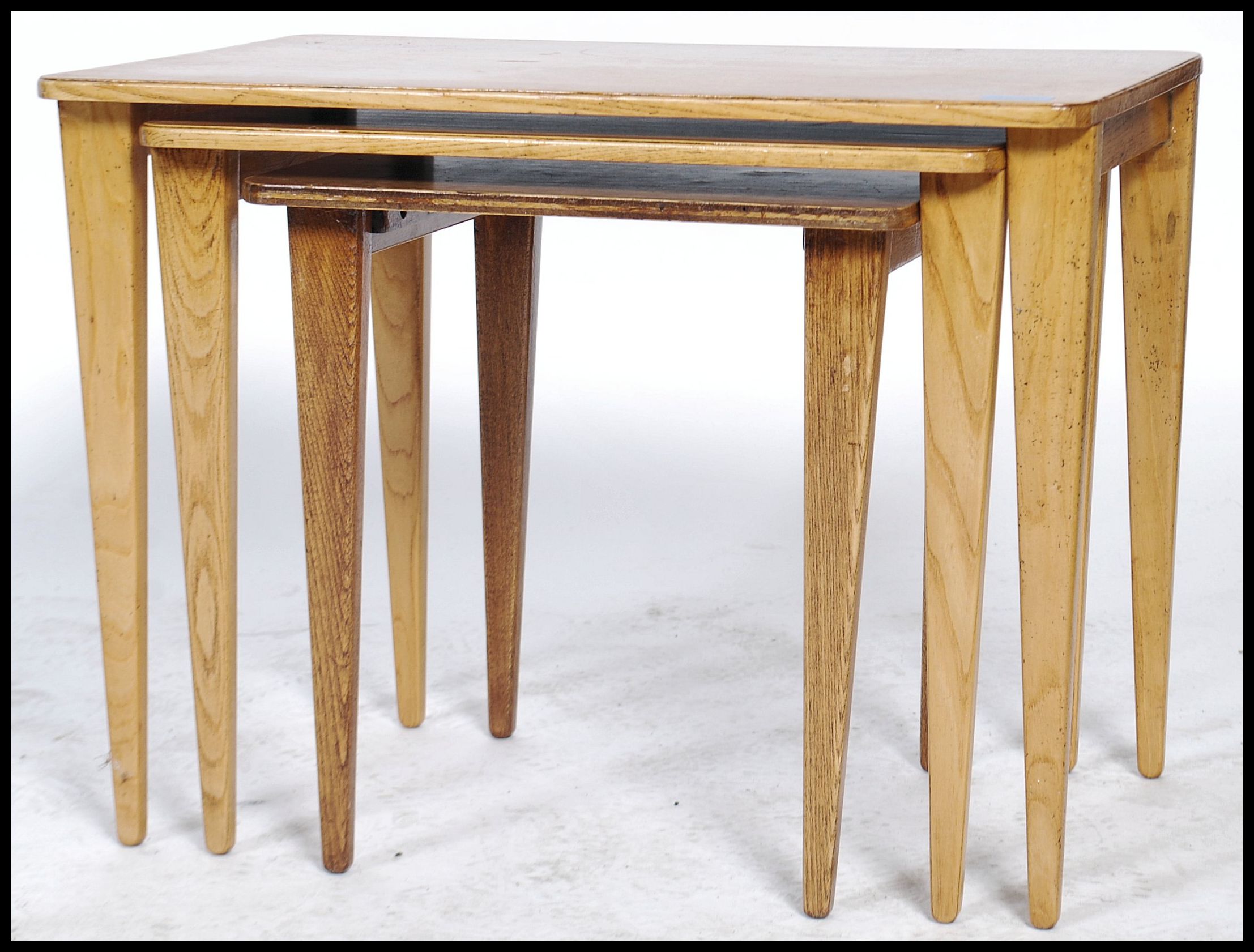 A vintage 20th century retro trio nest of tables with panel tops raised on square tapering legs with