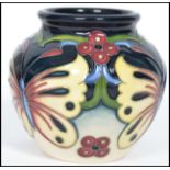 A Moorcroft tube lined squat vase decorated in the Burley Butterfly vase having a waisted neck