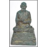 A 19th century Oriental figurine of an elder Buddha moulded in a praying position raised on a square