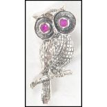 A silver 20th century brooch / pendant in the form of an owl inset with ruby stone eyes