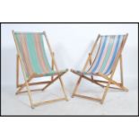 A pair of mid century deck chairs with wooden frames and a striped material hammock.
