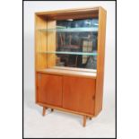 A 1960's teak open window display bookcase cabinet having a mirror back above a cupboard with