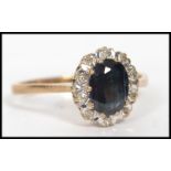 A 9ct gold, diamond and sapphire ring. The central sapphire of oval cut with a halo of diamonds