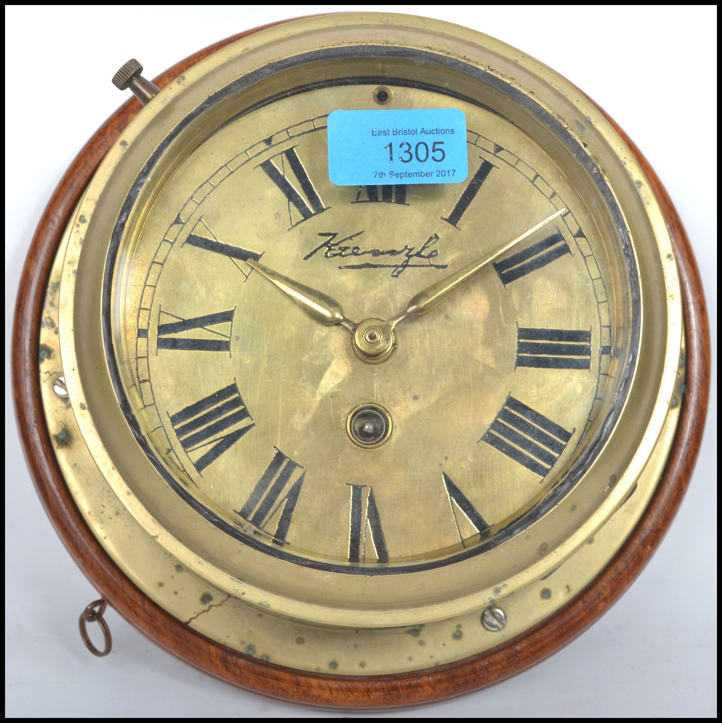A early 20th century brass bulkhead nautical ships clock having a roman numeral chapter ring,